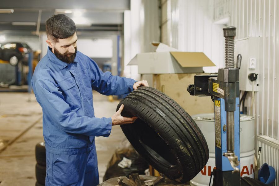Mechanic holding a tire next to a tire-changing machine